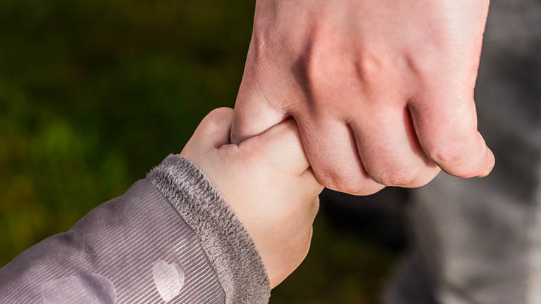 Image of a person holding a child's hand to illustrate noiminations of preneed guardian services from ASR Law Firm of South Florida.