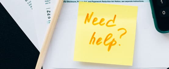 An image of a post it note asking the question "Need Help" from a  qualified trademark attorney over official trademark documents.