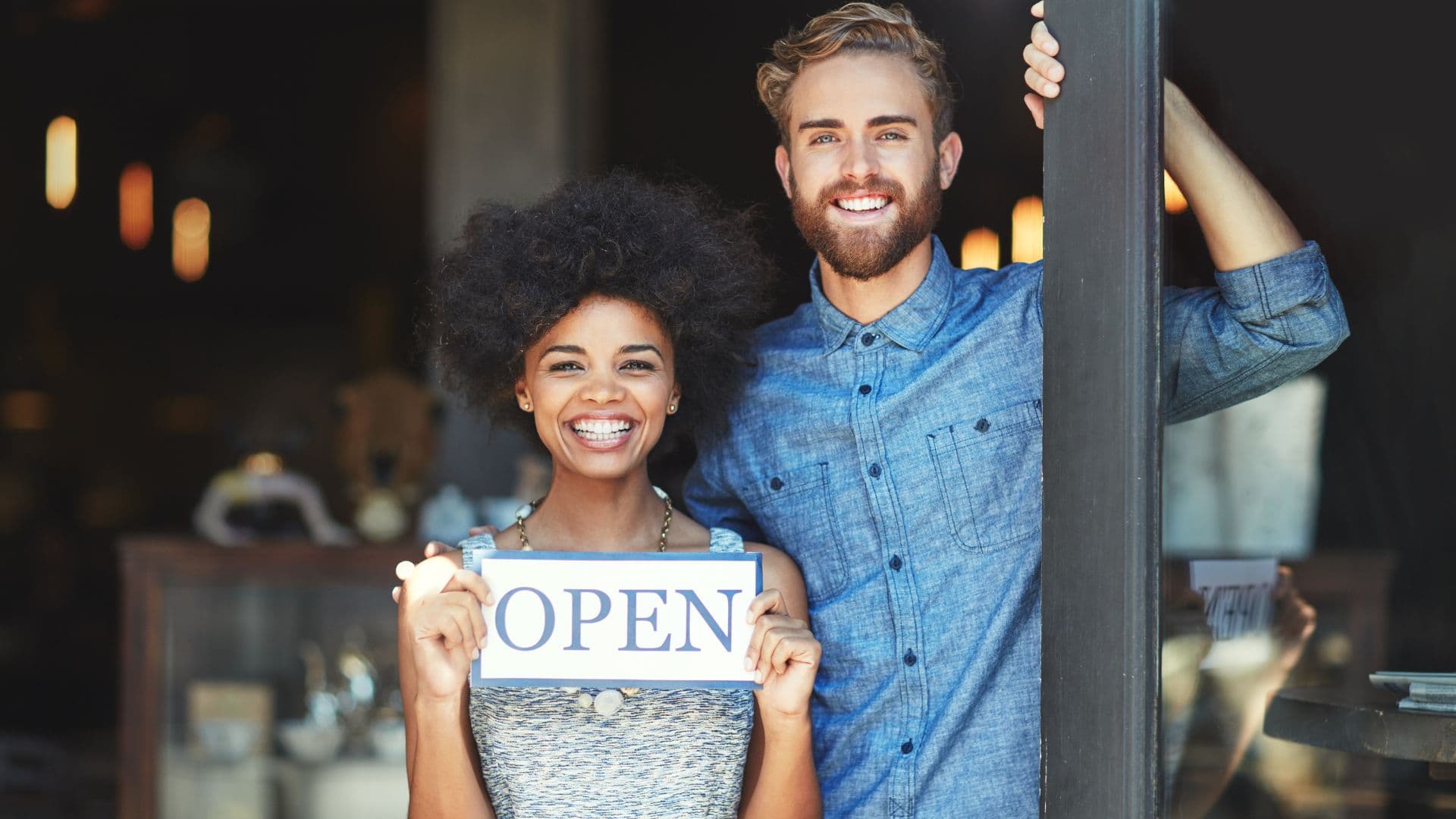 An image of two business owners holding an open for business sign in florida. 