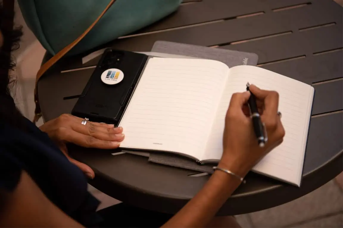 An image of attorney Anila S. Rasul writing in a journal while taking notes during consultation.