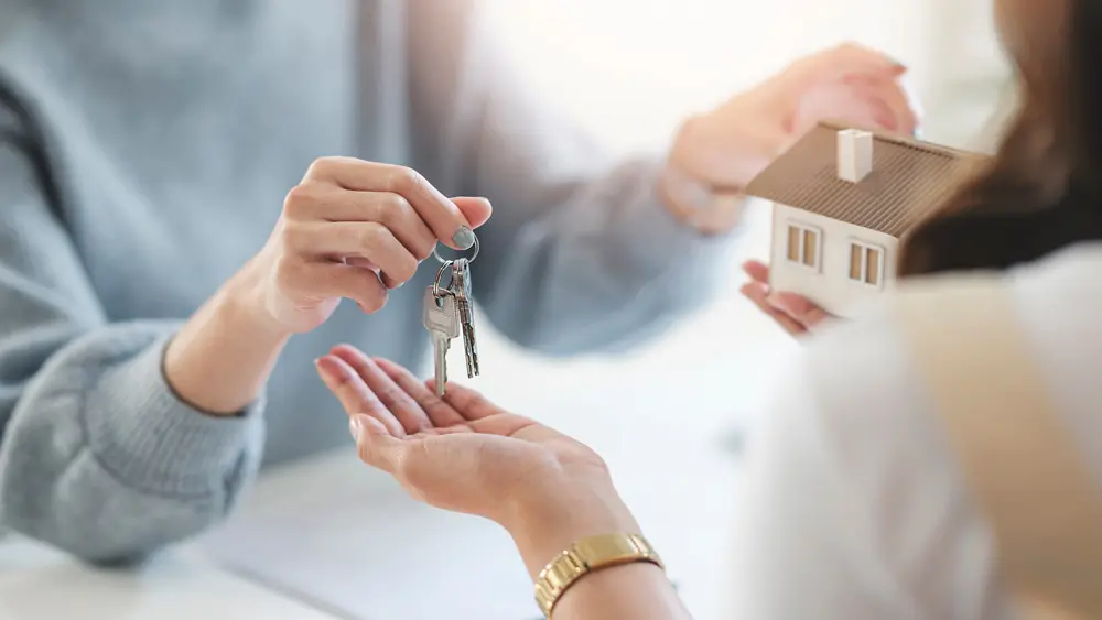 AN image of a person receiving the keys to their new house at a real estate closing. 