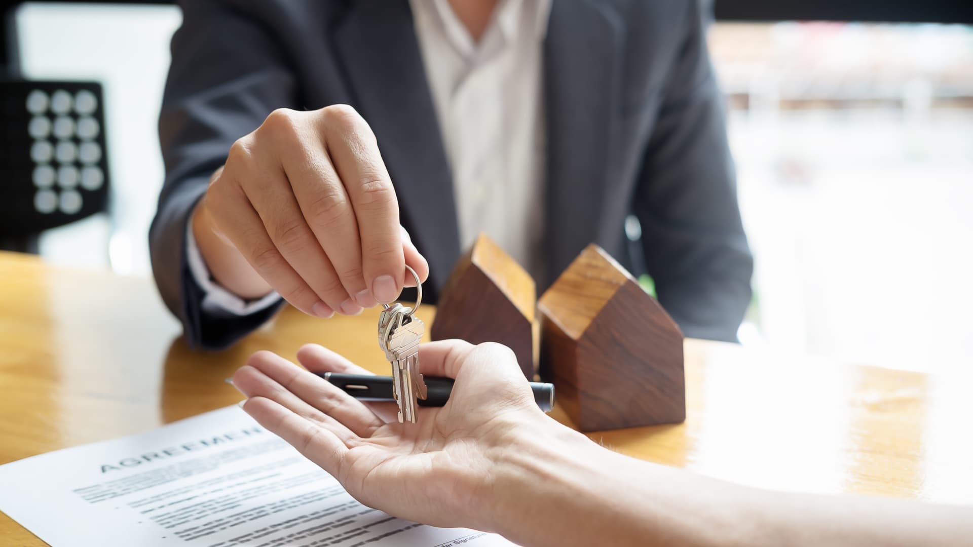 An image of a real estate closing agent handing the keys to a new house to a buyer. 