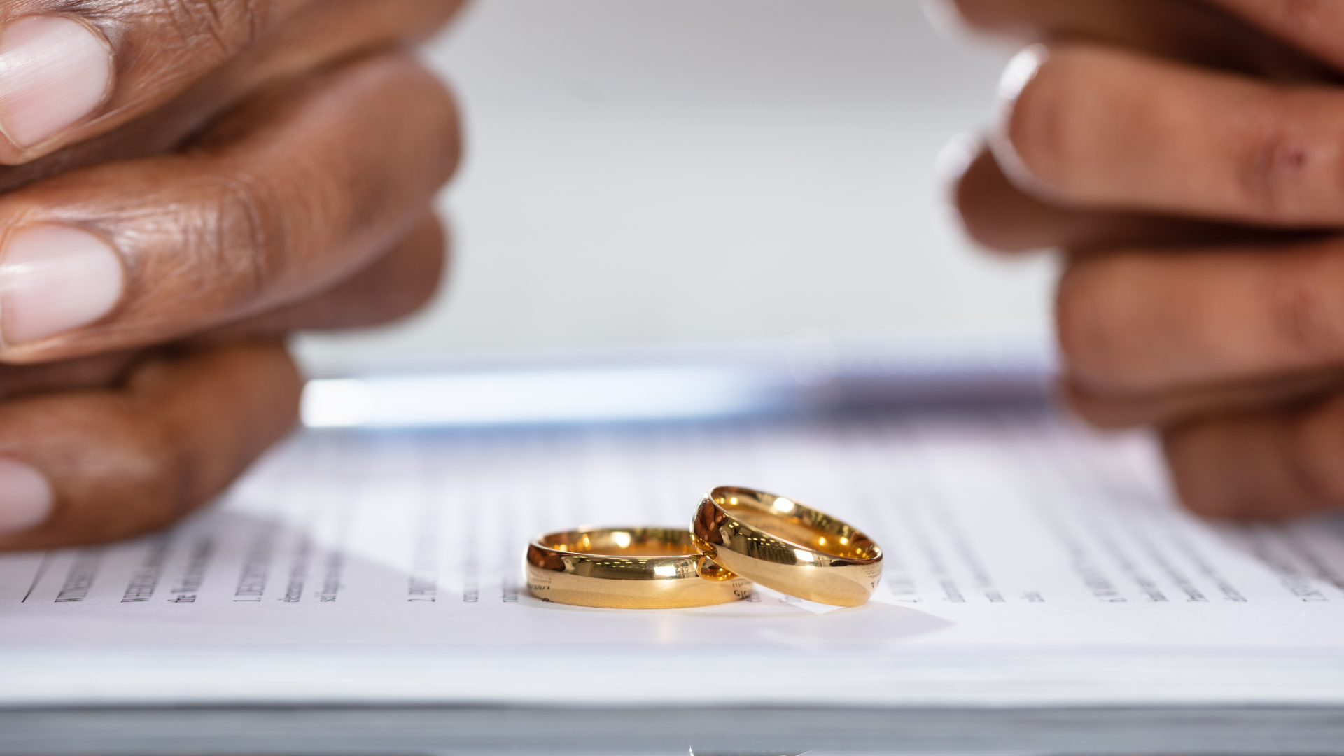 An image of a couple with their wedding rings off on a divorce document. 