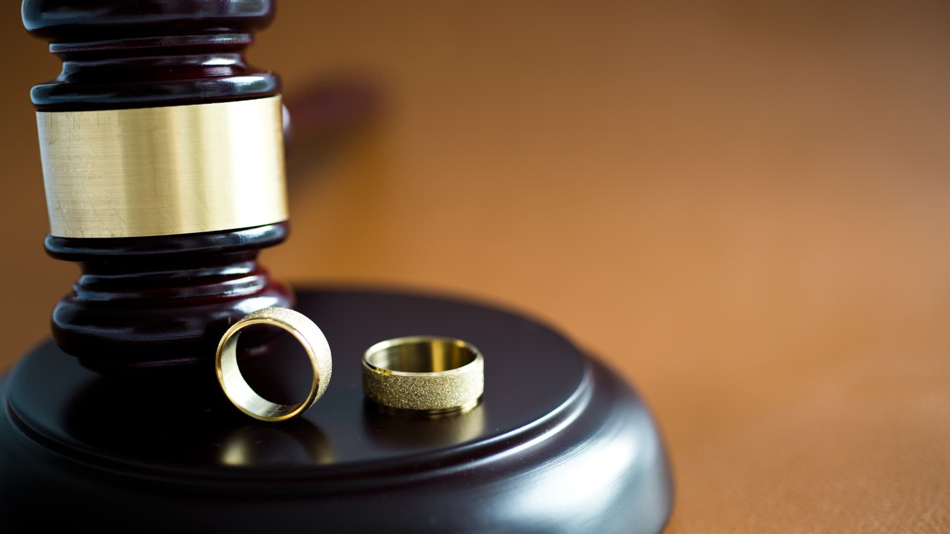 An image of two rings with a gavel showing divorce proceedings. 