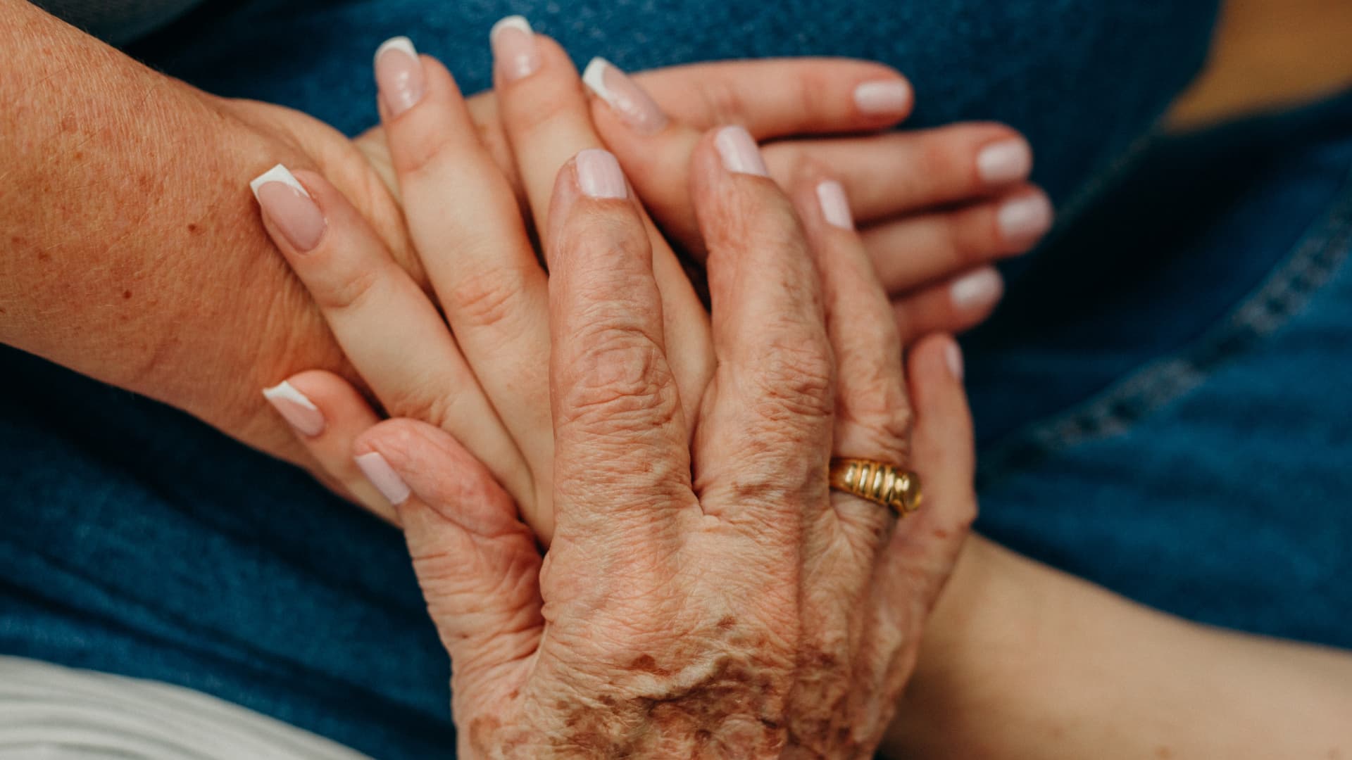An image of a older lady putting her hands on top of her daughter and granddaughter hands.
