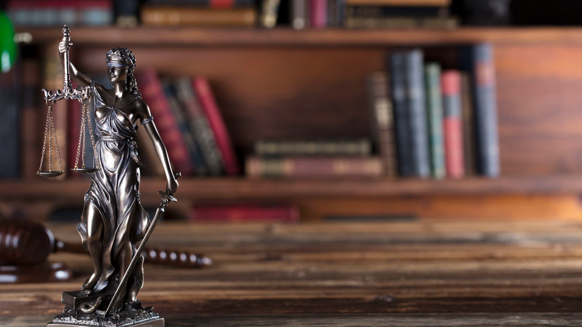 An image of a scales of justice with legal books in the background that reference piercing the corporate veil. 