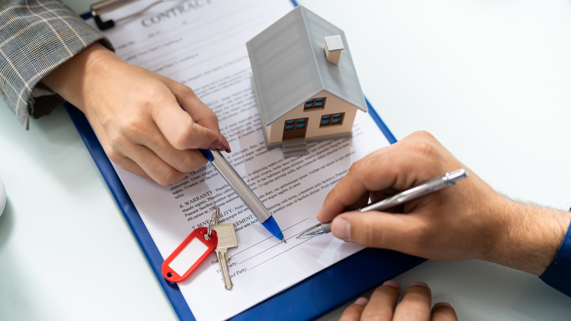 An image of a new home buyer signing a deed during a home sale. 