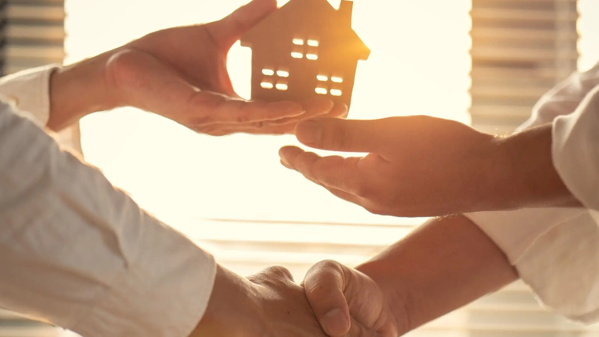 An image of a person handing a house model to another person showing real estate solutions from asr law firm.