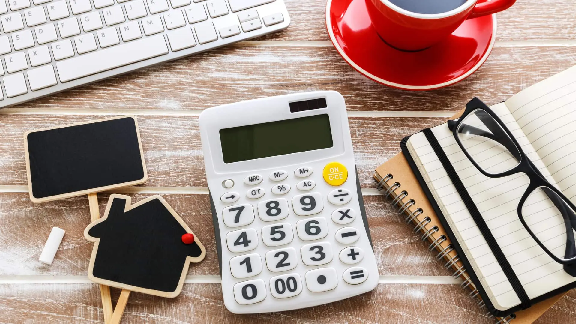 A desk with house icons and calculator for calculating real property transfer taxes in Florida.