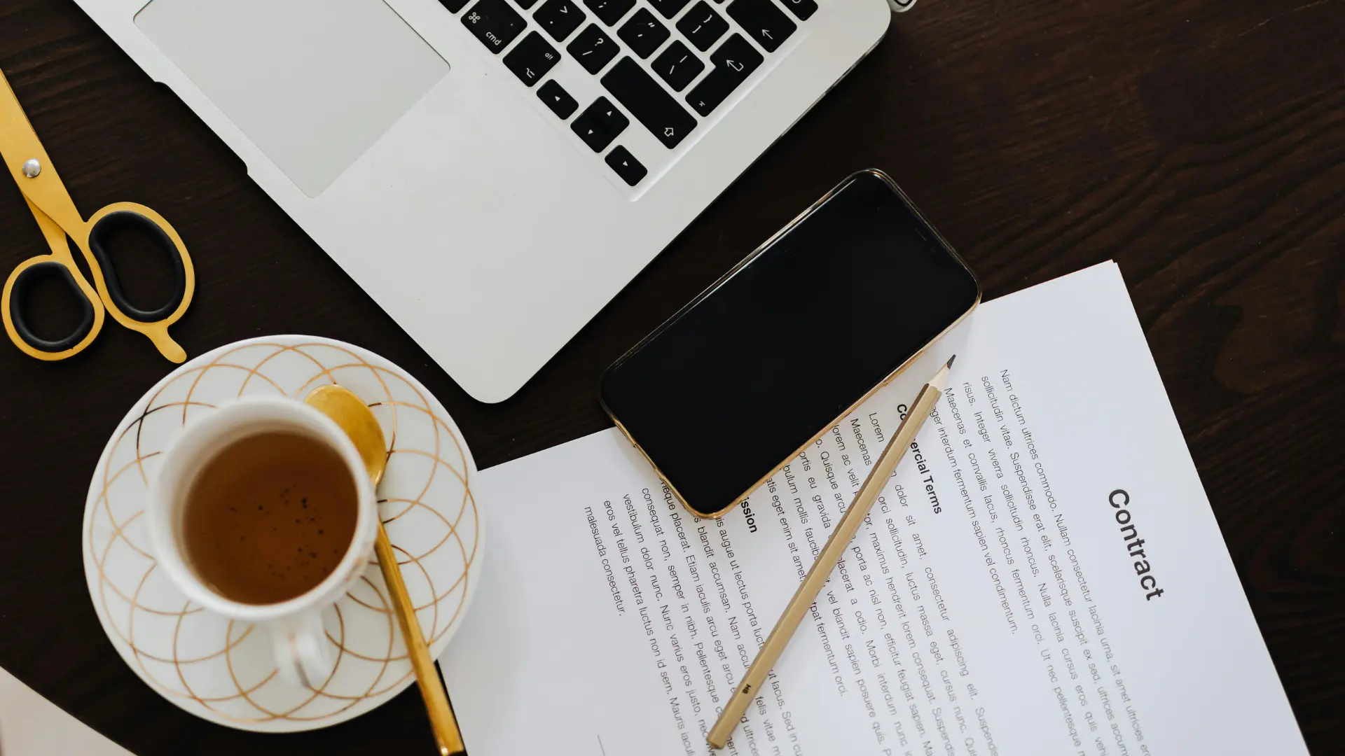 An image of a business contract on a desk next to a cup of tea and a laptop. 