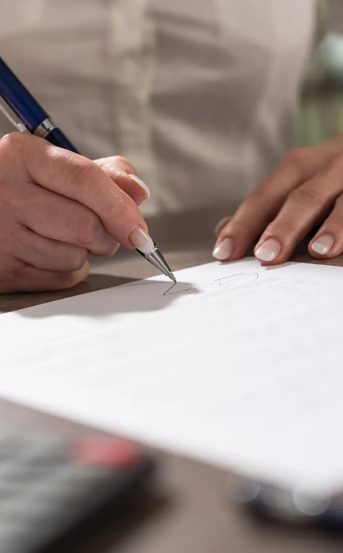 An image of a client signing a document at a FLorida Real Estate Attorney Office to transfer title. 