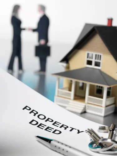 An image of a property deed with a house model illustrating the deed transfer and conveyance services provided by ASR Law Firm. 