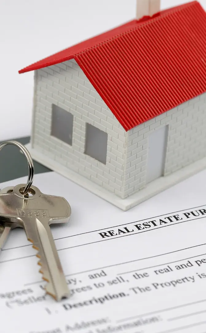 An image of a house model on top of a real estate contract with keys on the contract, showing the real estate contract services ASR Law Firm offers florida clients. 