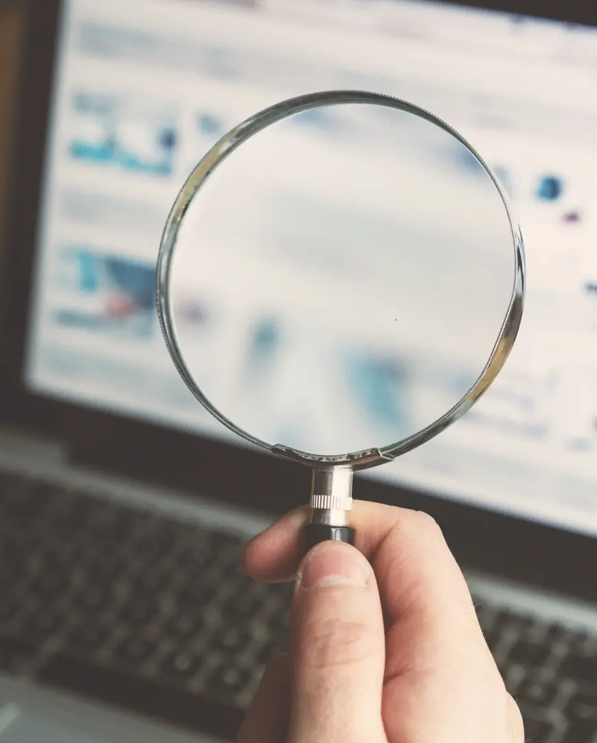 An image of a magnifying glass in front of a computer showing an attorney doing a title search. 