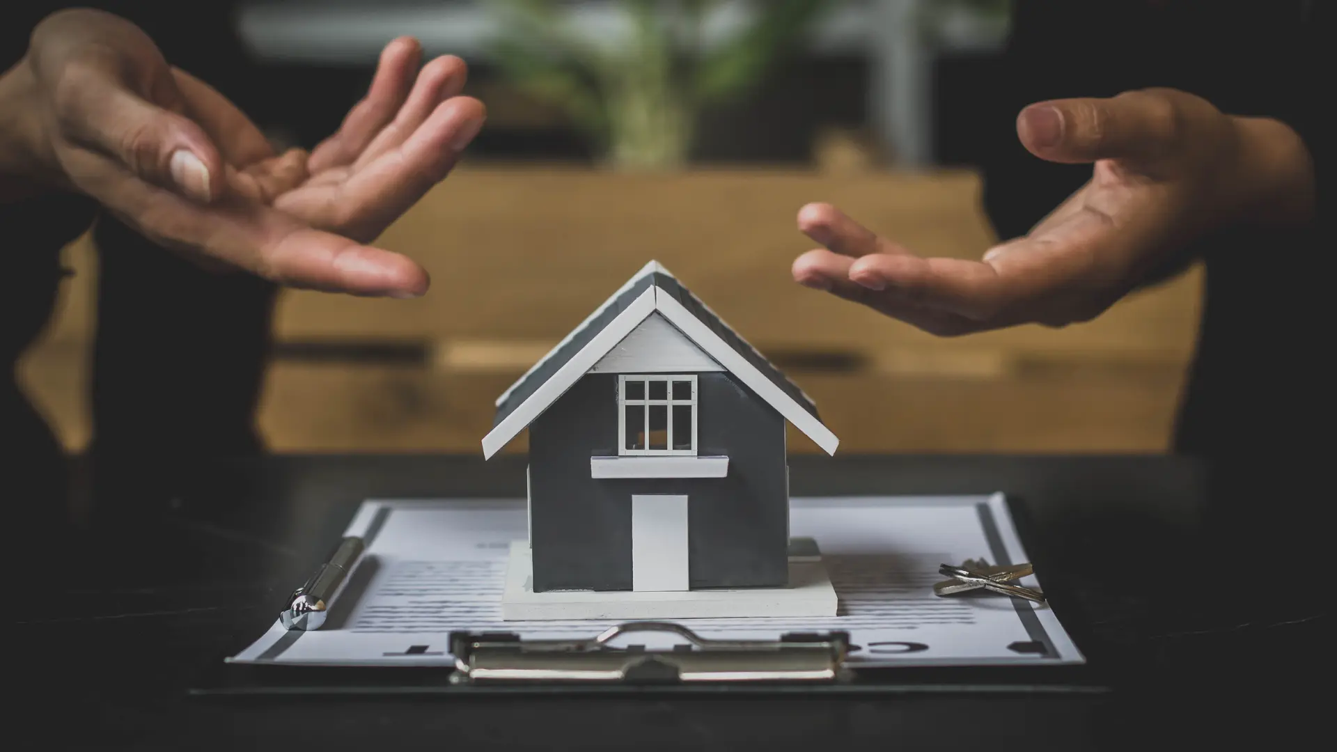 An image of people's hands showing discussions over a real estate property showing the options between lady bird deeds and revocable living trusts.
