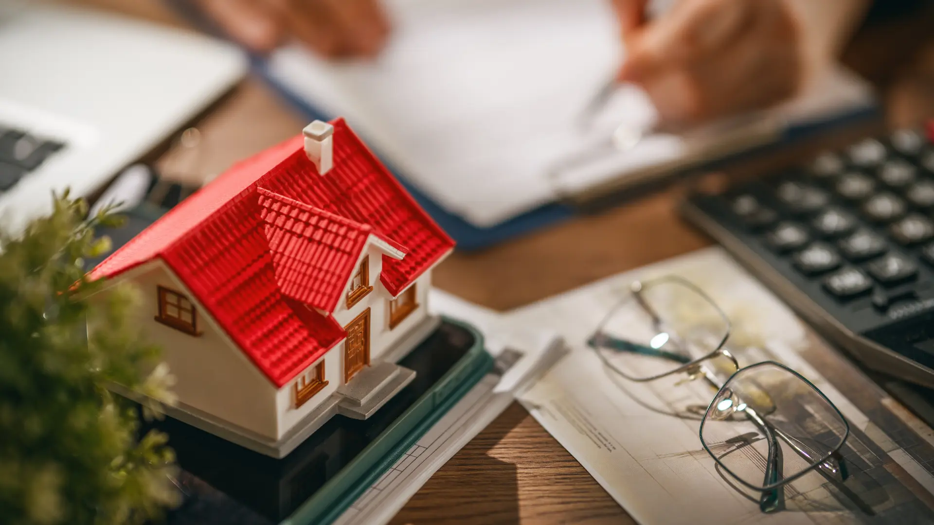 Model house next to a calculator and property documents, representing a Florida real estate investor evaluating Series LLC asset protection